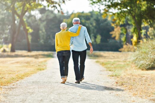 happy active senior couple walking and holding hands outdoors